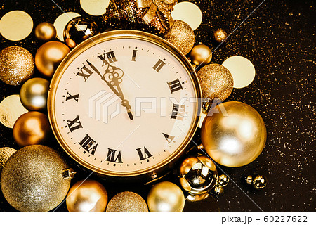 Gold vintage clock decorated with christmas balls on a black background in sparkles. Copy space 60227622