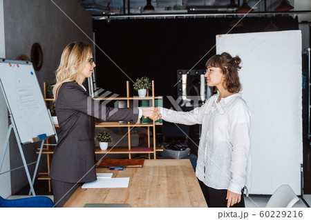 Two Businesswomen Shaking Hands In Office Two Businesswomen Shaking Hands In Office 60229216