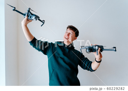 Guy holds two quadrocopters against a wall 60229282