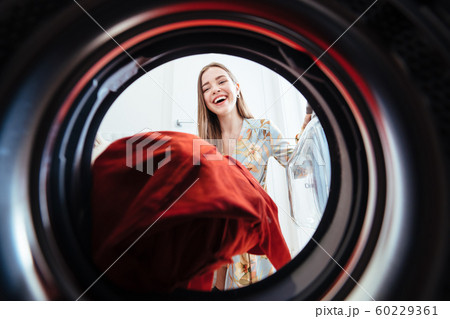 Young woman at home puts the dress in the drying machine. Young woman at home puts the dress in the drying machine. 60229361