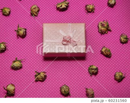 Photo flat lay gift box with bow among dried rose buds on a pink background top view Photo flat lay gift box with bow among dried rose buds on a pink background top view 60231560