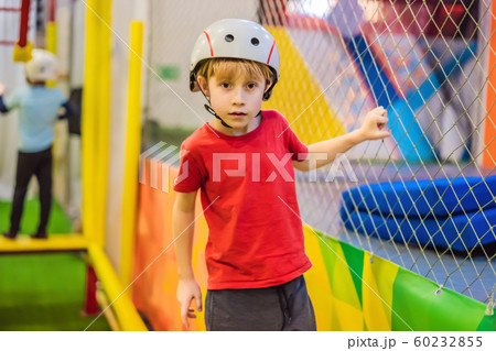 Portrait of 6 years old boy wearing helmet and climbing. Child in abstacle course in adventure Portrait of 6 years old boy wearing helmet and climbing. Child in abstacle course in adventure 60232855