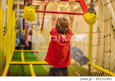 Portrait of 6 years old boy wearing helmet and climbing. Child in abstacle course in adventure Portrait of 6 years old boy wearing helmet and climbing. Child in abstacle course in adventure 60232881