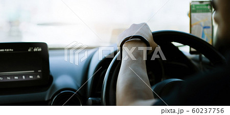 Close up of a man's hand holding the steering wheel of a car By using a smartphone 60237756