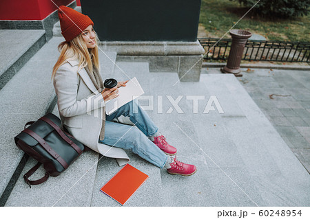 Pretty woman with copybooks and coffee outdoors 60248954