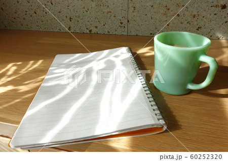 コーヒーカップと白紙のノート カーテン越しの光が射すテーブルで cup and notebook コーヒーカップと白紙のノート カーテン越しの光が射すテーブルで cup and notebook 60252320