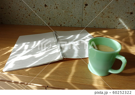 コーヒーカップと白紙のノート カーテン越しの光が射すテーブルで cup and notebook コーヒーカップと白紙のノート カーテン越しの光が射すテーブルで cup and notebook 60252322