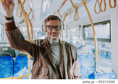 Handsome joyful man listening to music in public transport Handsome joyful man listening to music in public transport 60253986