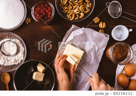 Woman's hands cut butter among ingredients Woman's hands cut butter among ingredients 60256212