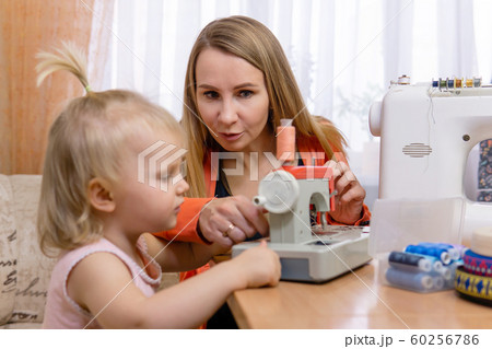 mom teaches little daughter to sew while playing mom teaches little daughter to sew while playing 60256786