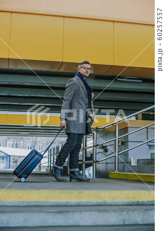 Handsome young man carrying travel suitcase and smiling 60257557