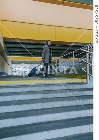 Stylish gentleman with trolley bag standing at railway station 60257558