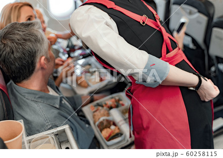 Stewardess is standing near passengers in cabin Stewardess is standing near passengers in cabin 60258115