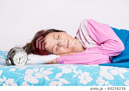 Girl in her bed sleeping next to the alarm clock Girl in her bed sleeping next to the alarm clock 60258236