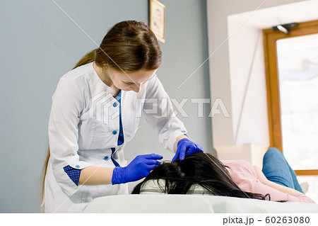 Procedure of mesotherapy. Young woman doctor cosmetologist making injections in woman's head for stronger and healthier hair. Procedure of mesotherapy. Young woman doctor cosmetologist making injections in woman's head for stronger and healthier hair. 60263080
