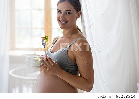 Smiling pretty expectant mother going to eat vegetables Smiling pretty expectant mother going to eat vegetables 60263514