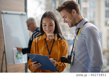 Female dark-haired reporter showing notes to her colleague Female dark-haired reporter showing notes to her colleague 60273851