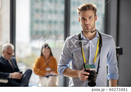 Young man in a blue shirt holding his camera Young man in a blue shirt holding his camera 60273881