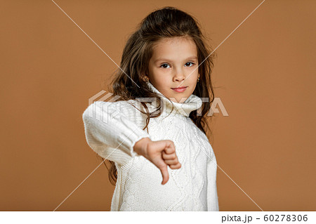 child girl in white sweater showing the thumbs down 60278306