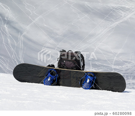 Snowboard and black backpack on snow in high Snowboard and black backpack on snow in high 60280098