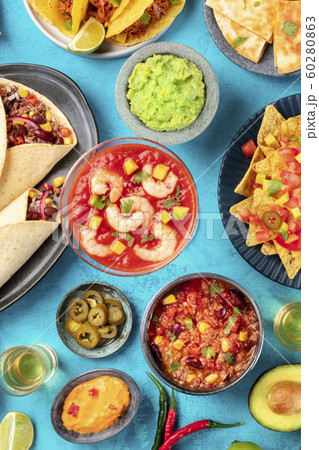 Mexican food, overhead flatlay shot on a vibrant blue background. Shrimp cocktail, chili con carne, guacamole and other dishes 60280863