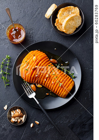 Roasted pumpkin with honey glaze and herbs on a black plate. Slate background. Top view. 60283769