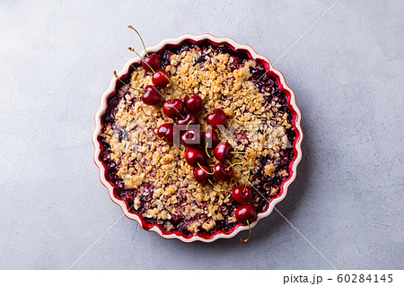 Cherry, red berry crumble in baking dish. Grey stone background. Top view. Cherry, red berry crumble in baking dish. Grey stone background. Top view. 60284145