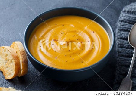 Pumpkin, carrot cream soup in a bowl. Grey background. Close up. 60284207