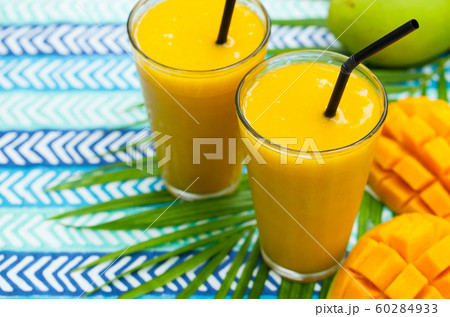 Fresh tropical fruit smoothie mango juice and fresh mango. Blue textile background. Copy space. Fresh tropical fruit smoothie mango juice and fresh mango. Blue textile background. Copy space. 60284933