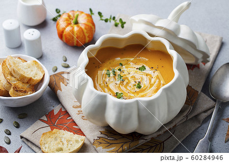 Pumpkin and carrot cream soup in creative bowl. Grey background. Close up. Pumpkin and carrot cream soup in creative bowl. Grey background. Close up. 60284946