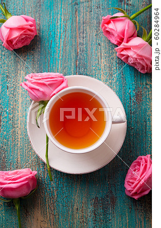 Cup of tea with pink rose. Colorful turquoise wooden background. Top view. 60284964