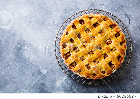 Apple pie with caramel on a cooling rack. Grey background. Copy space. Top view. Apple pie with caramel on a cooling rack. Grey background. Copy space. Top view. 60285937