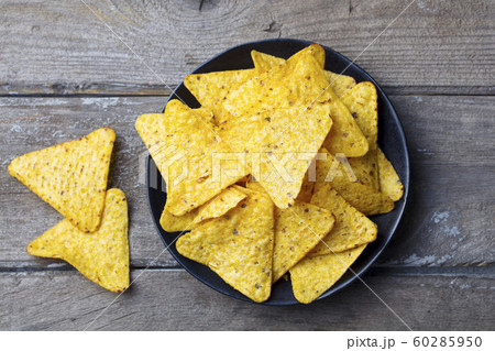 Nachos, corn chips on black plate. Wooden background. Top view. Nachos, corn chips on black plate. Wooden background. Top view. 60285950
