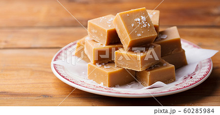 Caramel fudge candies on a plate. Wooden background. Close up. 60285984