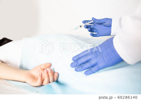 Doctor proctologist treats a patient for hemorrhoids with the help of modern method sclerotherapy, white background, copy space, painlessness 60286140