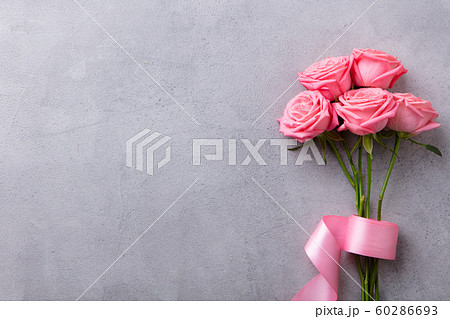 Pink roses with pink ribbon on grey stone background. Top view. Copy space. Pink roses with pink ribbon on grey stone background. Top view. Copy space. 60286693