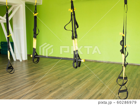 Modern fitness room for practicing hinges on the TRX for strengthening the muscular corset and burning calories, copy space Modern fitness room for practicing hinges on the TRX for strengthening the muscular corset and burning calories, copy space 60286979