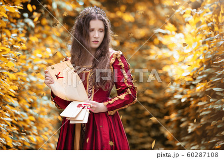 Sad woman in a red dress reading a letter Sad woman in a red dress reading a letter 60287108