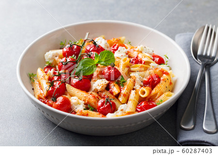 Pasta penne with roasted tomato, sauce, mozzarella cheese. Grey stone background. Close up. Pasta penne with roasted tomato, sauce, mozzarella cheese. Grey stone background. Close up. 60287403