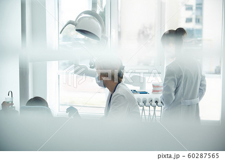 Dentist and assistant are seeing patient in office Dentist and assistant are seeing patient in office 60287565