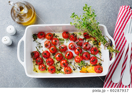 Roasted cherry tomatoes with herbs in baking dish. Grey background. Top view. Roasted cherry tomatoes with herbs in baking dish. Grey background. Top view. 60287937
