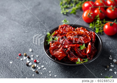 Sun dried tomatoes with fresh herbs and spices. Slate background. Copy space. 60288523