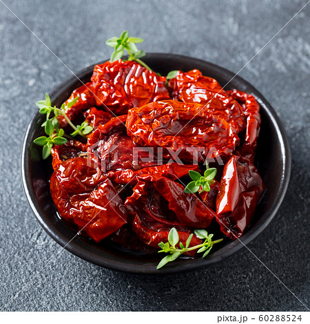 Sun dried tomatoes with fresh herbs and spices. Slate background. Close up. Top view. 60288524