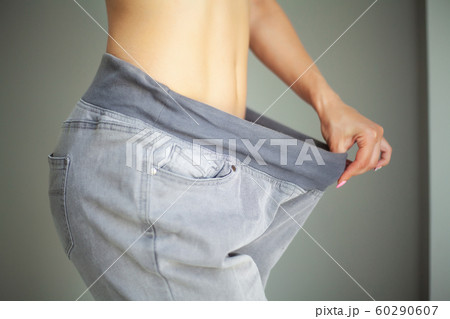 Diet concept. Slim girl after diet in old big jeans 60290607