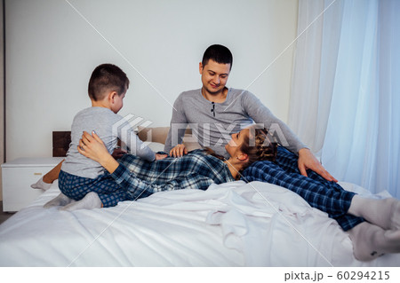 mom dad son in the morning in bed 60294215