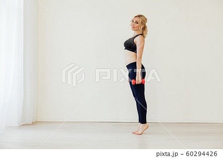 Blonde woman engaged in fitness with dumbbells in sports hall 60294426