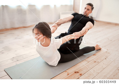 Man and woman duo doing yoga stretching exercises seated twisting their  bodies to face each other with raised hands in a low angle view Stock Photo  - Alamy