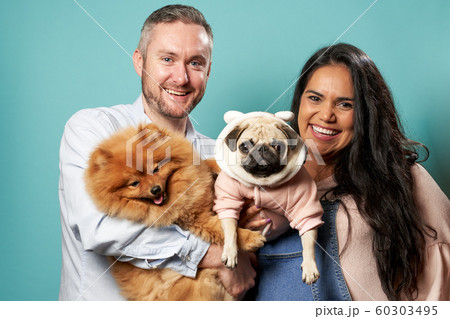 Young pregnant woman and man hold dogs on hands on green background Young pregnant woman and man hold dogs on hands on green background 60303495