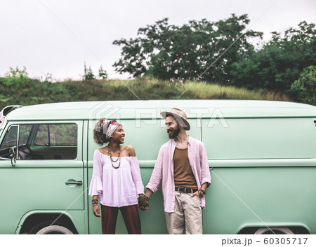 Happy ethnicity couple staying near retro mini van Happy ethnicity couple staying near retro mini van 60305717