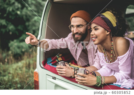 Beloved couple laying in retro van with cup of tea 60305852